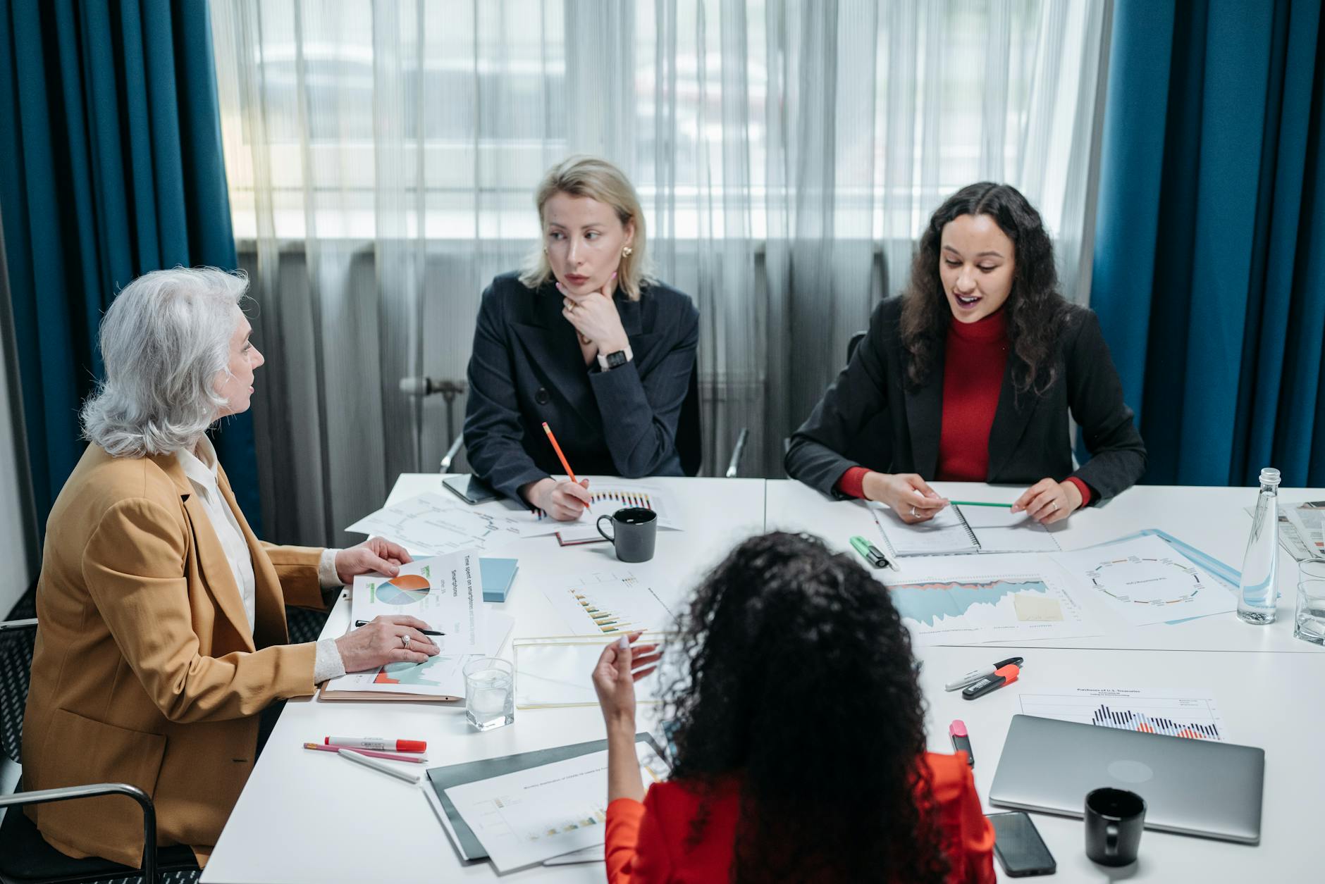 Lider introwertyk kontra lider ekstrawertyk: różne drogi do skutecznego przywództwa Cztery bizneswoman omawiające strategię przywództwa przy biurku